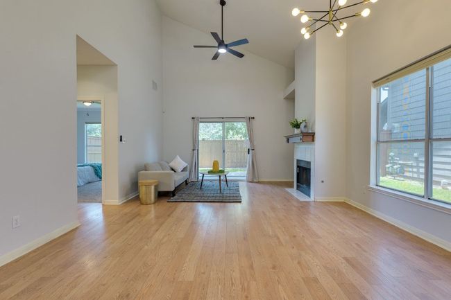 Living area featuring plenty of natural light, a fireplace with flush hearth, high vaulted ceiling, and light wood-style floors | Image 7
