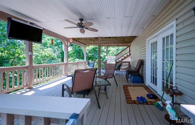 Wooden terrace featuring outdoor dining area, french doors, a ceiling fan, and stairway | Image 52