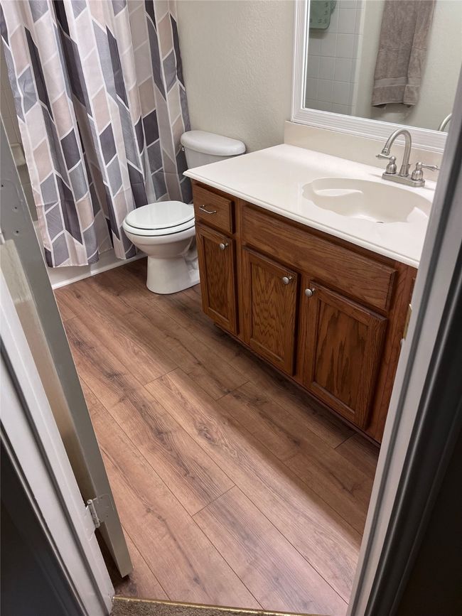 Bathroom featuring wood look floors, vanity, toilet, and curtained shower | Image 24