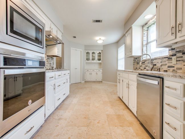 Kitchen featuring appliances with stainless steel finishes, backsplash, a sink, and white cabinetry | Image 6