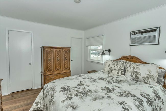 Bedroom featuring dark wood-style flooring, an AC wall unit, and crown molding | Image 20
