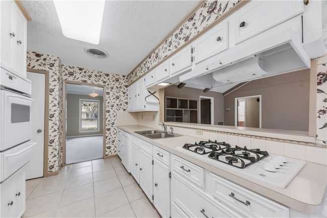 Kitchen with wallpapered walls, white appliances, a textured ceiling, light countertops, and a warming drawer | Image 7