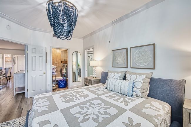 Bedroom with a chandelier, ornamental molding, wood finished floors, and a closet | Image 28