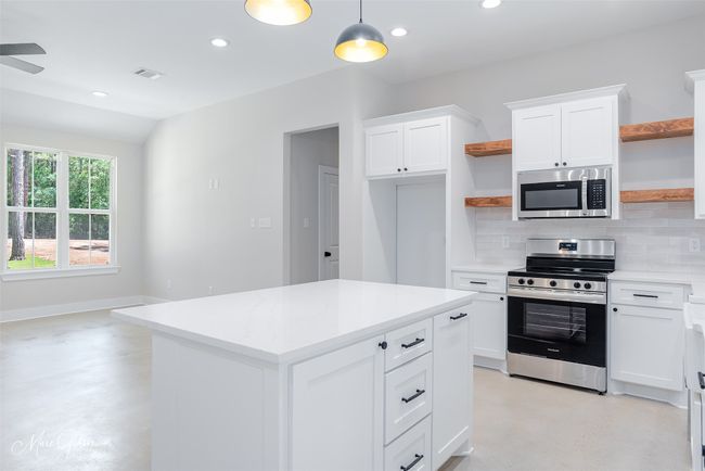Kitchen featuring open shelves, concrete flooring, and stainless steel appliances | Image 5
