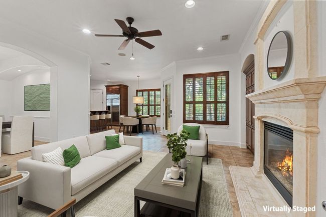 Living room featuring a premium fireplace, a ceiling fan, recessed lighting, ornamental molding, and arched walkways | Image 11