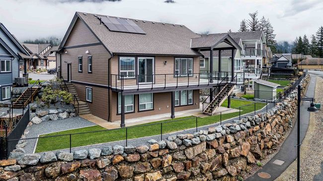 Rear view of house featuring a patio area, stairway, a fenced backyard, solar panels, and a lawn | Image 38