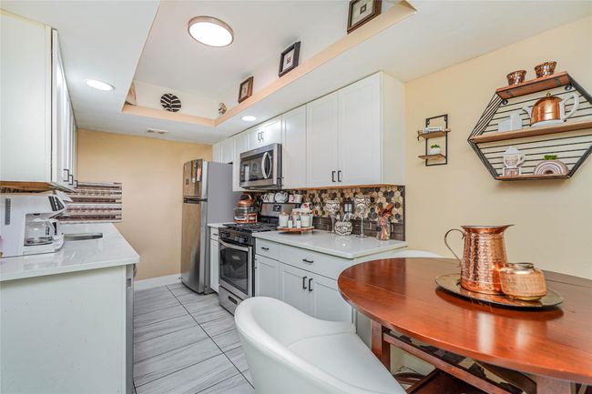 Kitchen featuring stainless steel appliances, backsplash, light countertops, and white cabinets | Image 6