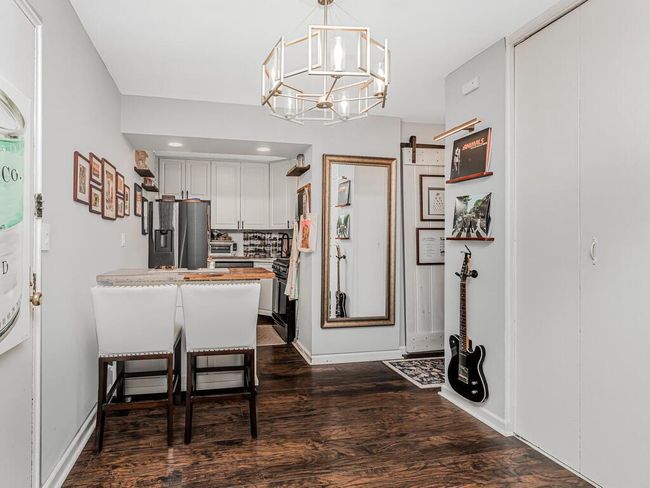 Kitchen featuring stainless steel refrigerator with ice dispenser, dark wood-type flooring, a chandelier, a peninsula, and hanging light fixtures | Image 14