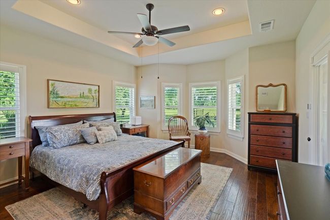 Bedroom featuring a raised ceiling, dark wood-style flooring, baseboards, recessed lighting, and ceiling fan | Image 12
