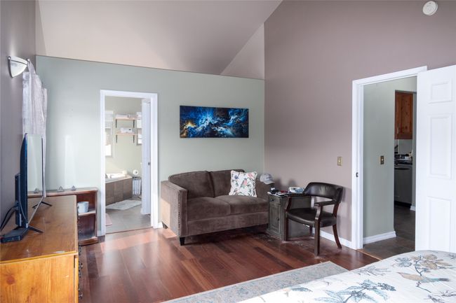 Bedroom with ensuite bathroom, baseboards, wood finished floors, and lofted ceiling | Image 44