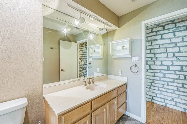 Bathroom with wood finished floors, toilet, a textured wall, and vanity | Image 24