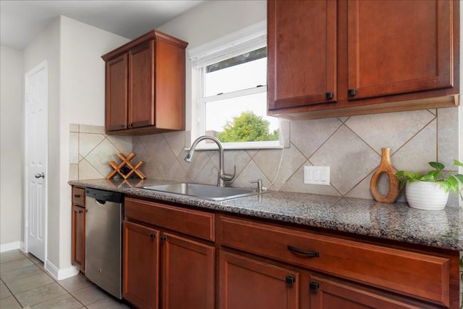 Kitchen featuring dishwasher, a sink, light tile patterned floors, backsplash, and baseboards | Image 9