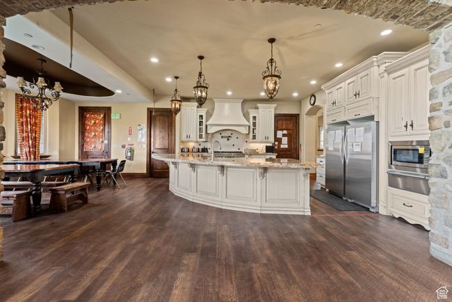Kitchen featuring premium range hood, appliances with stainless steel finishes, an inviting chandelier, and dark wood-style flooring | Image 17