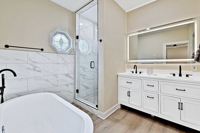Full bathroom with a sink, a stall shower, double vanity, a soaking tub, and wood finished floors | Image 15