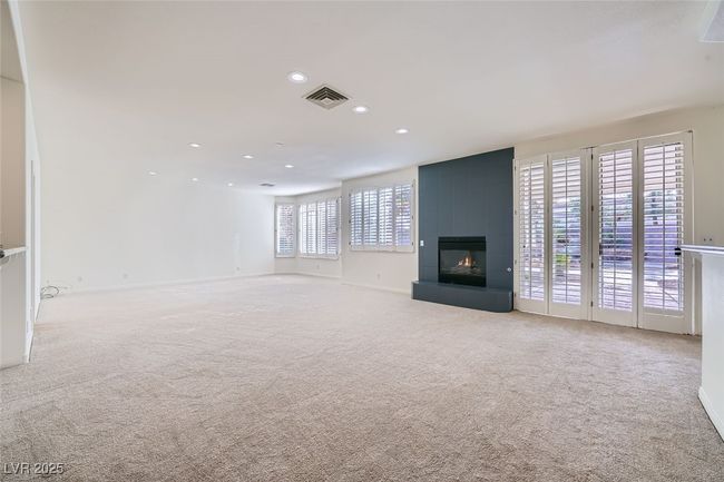 Unfurnished living room featuring light carpet, a fireplace, visible vents, and recessed lighting | Image 31