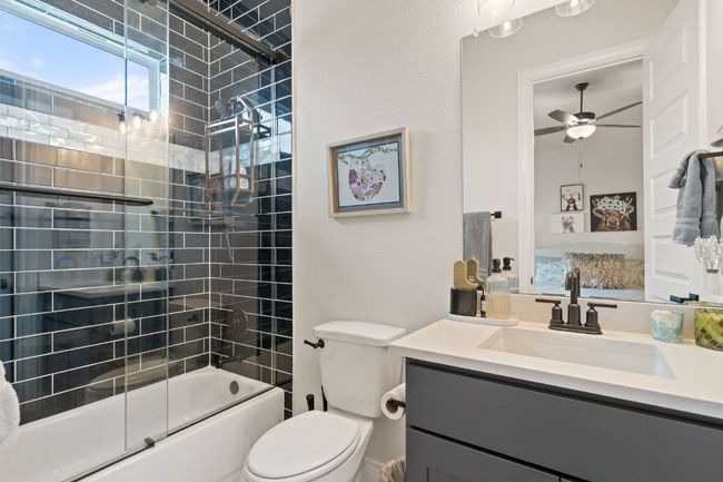 Full bath featuring toilet, enclosed tub / shower combo, a ceiling fan, and vanity | Image 24