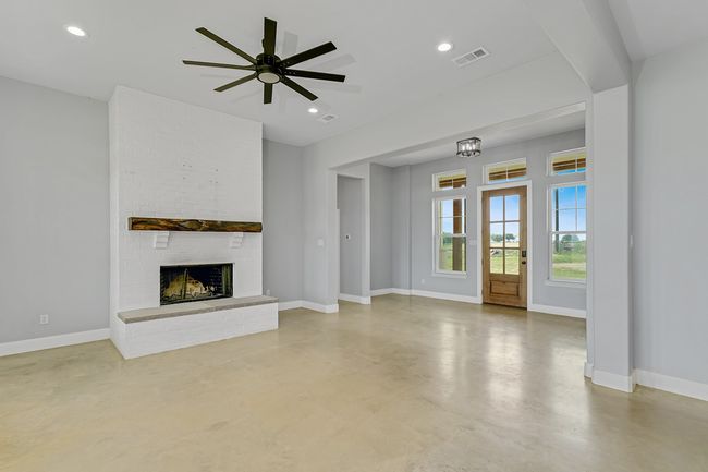 Unfurnished living room featuring finished concrete floors, baseboards, a brick fireplace, ceiling fan, and recessed lighting | Image 8