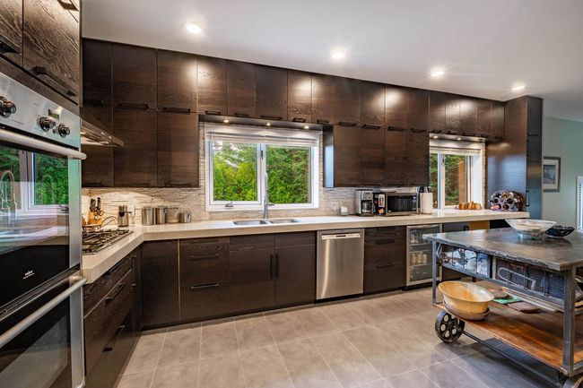 Kitchen featuring appliances with stainless steel finishes, beverage cooler, light countertops, decorative backsplash, and recessed lighting | Image 11
