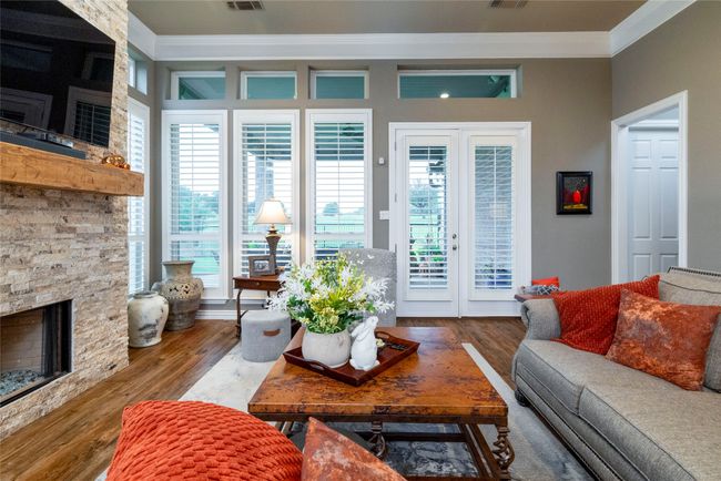 Living room featuring plantation shutters and door out to covered patio. | Image 14