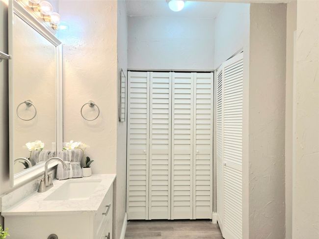 Bathroom with vanity, a closet, wood finished floors, and a textured wall | Image 15