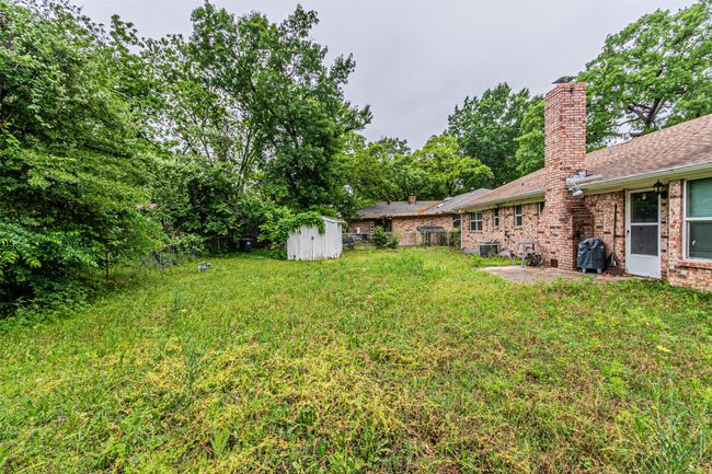 View of yard featuring an outbuilding, a shed, a fenced backyard, and a patio area | Image 30