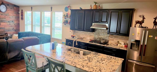 Kitchen featuring stainless steel fridge with ice dispenser, plenty of natural light, under cabinet range hood, and decorative backsplash | Image 10