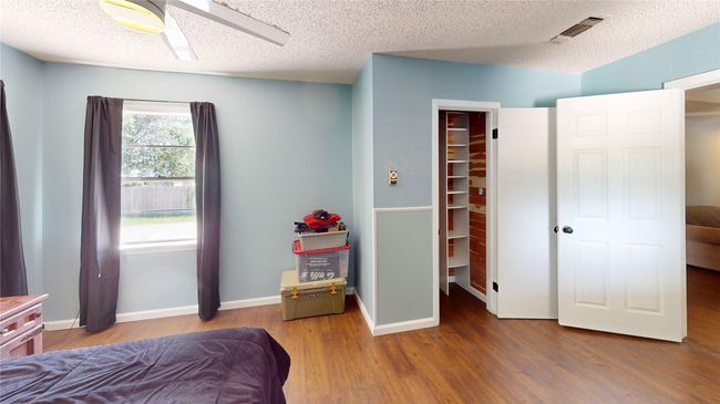 Bedroom with wood finished floors, a textured ceiling, and a spacious closet | Image 22
