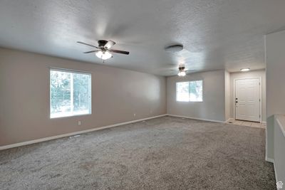 Unfurnished room featuring light colored carpet, ceiling fan, and a textured ceiling | Image 2