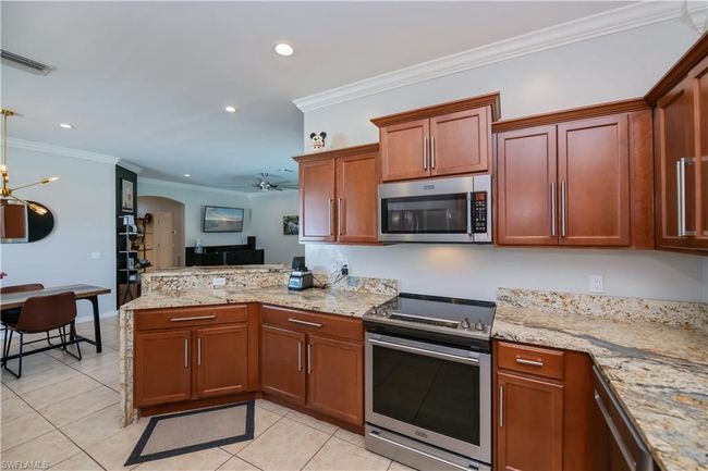 Kitchen featuring crown molding, a peninsula, recessed lighting, appliances with stainless steel finishes, and light tile patterned floors | Image 9