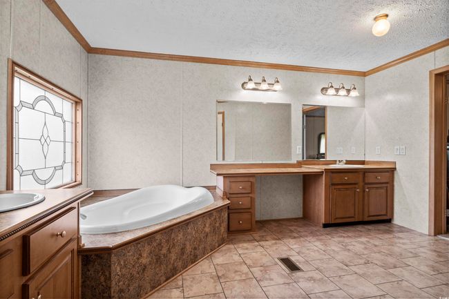Full bath with crown molding, two vanities, a bath, and a textured ceiling | Image 33