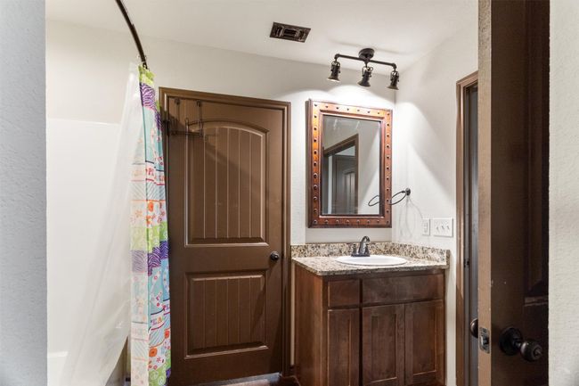 Bathroom featuring real wood vanity with granite countertop and a shower tub combo | Image 7