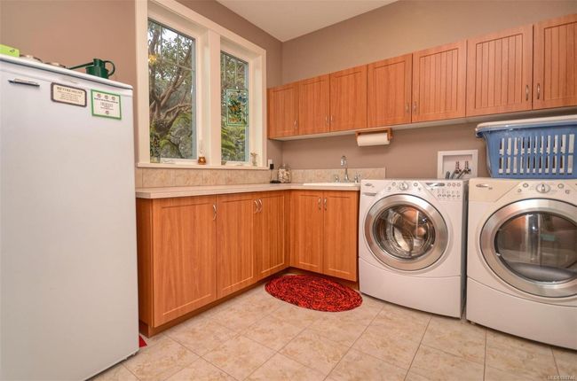 Laundry room featuring light tile patterned floors, cabinets, washer, dryer, and sink | Image 11
