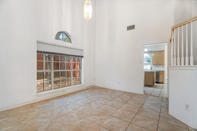 Unfurnished room with a towering ceiling, visible vents, and light tile patterned flooring | Image 12