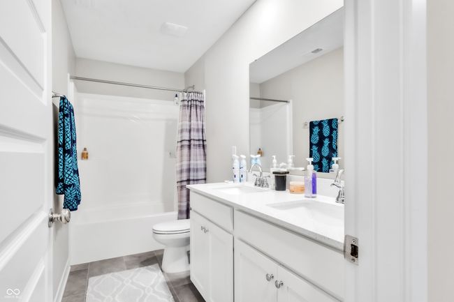 full bath featuring shower / bath combination with curtain, tile patterned floors, double vanity, and a sink | Image 25