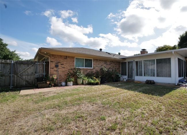 Back of house featuring a sunroom, a chimney, brick siding, and a gate | Image 29