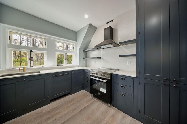 Kitchen featuring a sink, open shelves, ventilation hood, light wood-style flooring, and stainless steel electric stove | Image 18
