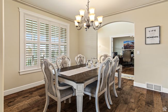 Dining space with ornamental molding, dark wood-type flooring, and a notable chandelier | Image 23