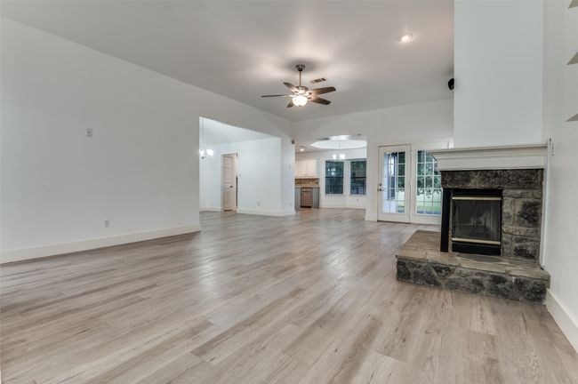 Unfurnished living room featuring a fireplace, ceiling fan, light wood-style floors, and french doors | Image 5