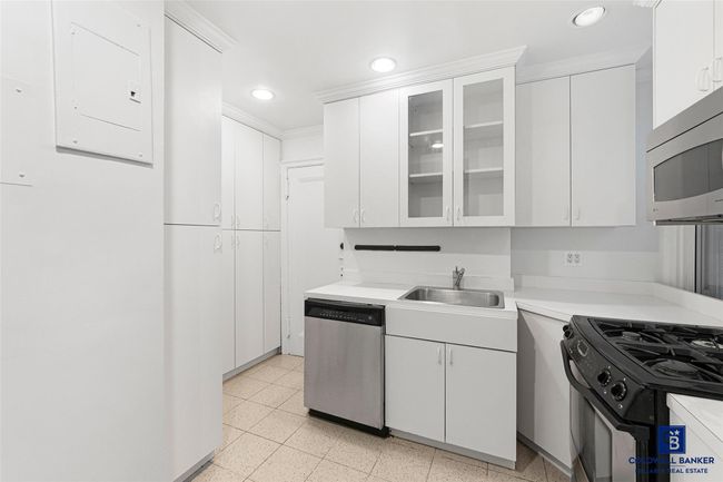 Kitchen with light countertops, a sink, glass insert cabinets, appliances with stainless steel finishes, and white cabinetry | Image 9