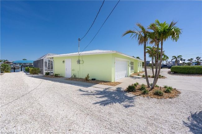 View of property exterior featuring driveway, stucco exterior, attached garage, and zero scaping with tropical flare | Image 21