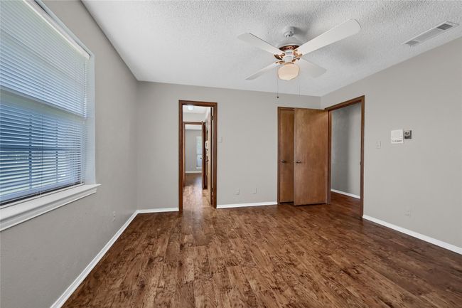 Unfurnished bedroom featuring a textured ceiling, wood finished floors, baseboards, and visible vents | Image 25