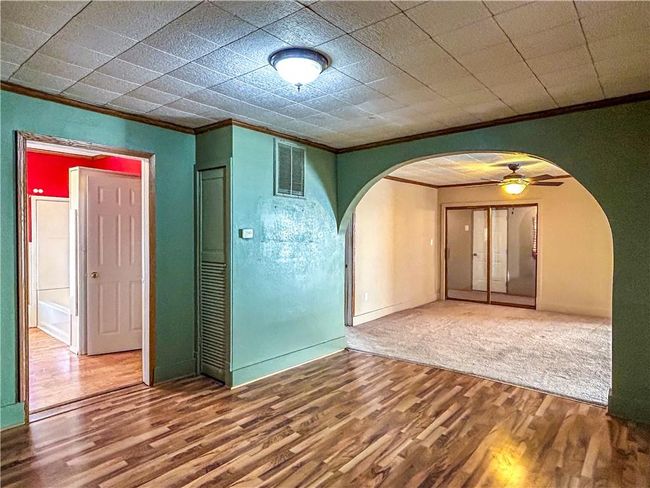 Empty room featuring ornamental molding, arched walkways, visible vents, and wood finished floors | Image 9