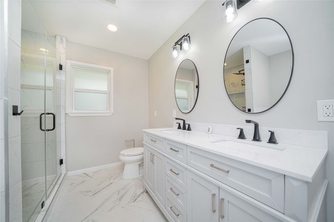 Bathroom with double vanity, a stall shower, marble finish flooring, and recessed lighting | Image 25