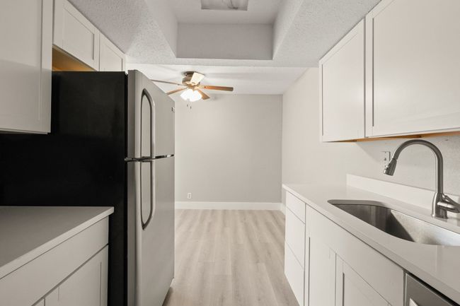 Kitchen with stainless steel appliances, light wood-style flooring, a ceiling fan, and white cabinetry | Image 8