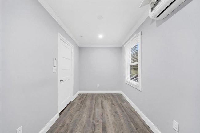 Unfurnished room with an AC wall unit, crown molding, wood finished floors, and baseboards | Image 16