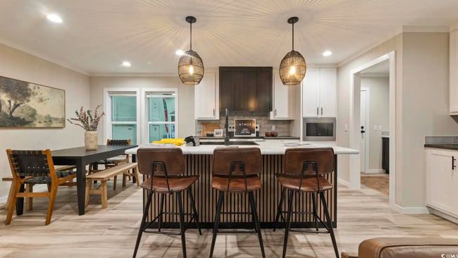 Kitchen featuring light wood-style floors, white cabinetry, a kitchen bar, stainless steel microwave, and recessed lighting | Image 19
