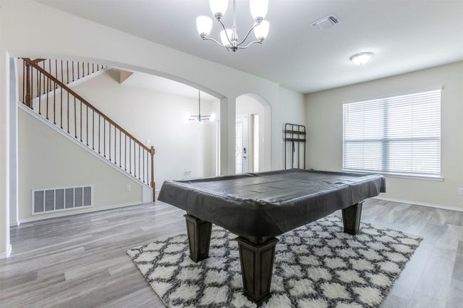 Recreation room featuring visible vents, arched walkways, light wood-style floors, and a notable chandelier | Image 10