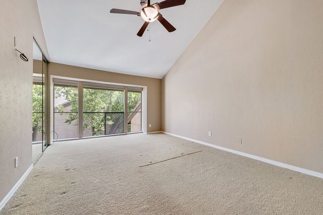 Carpeted empty room with ceiling fan, high vaulted ceiling, and baseboards | Image 17