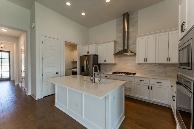 Kitchen featuring stainless steel appliances, wall chimney range hood, decorative backsplash, dark wood-style flooring, and recessed lighting | Image 14