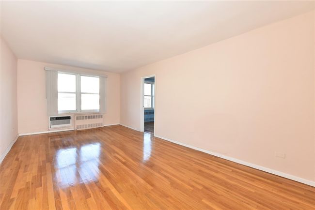 Unfurnished room featuring a wall mounted AC, radiator, and light hardwood / wood-style flooring | Image 6